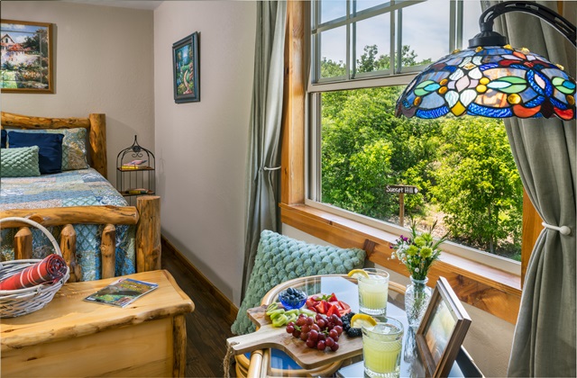 Astoria room view with bistro table and chairs with a view of fruit tray and lemonade.